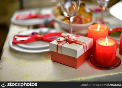 table setting with candles. fork, knife and red napkin on dish