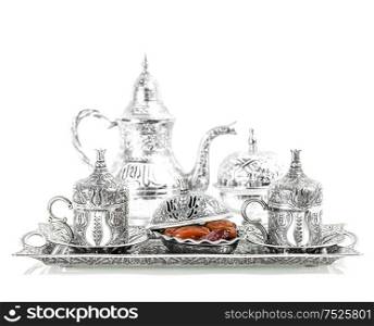 Table setting with silver tableware and dates. Oriental hospitality concept with tea or coffee cups. High key picture