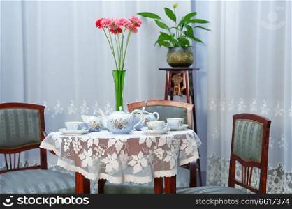 Table setting with tea service and flowers in vase
