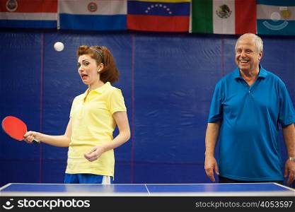Table tennis coach laughing at student playing