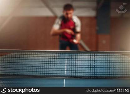 Table tennis net, selective focus, male player on background. Ping pong training indoor