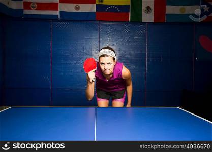 Table tennis player with bat bending forward at table