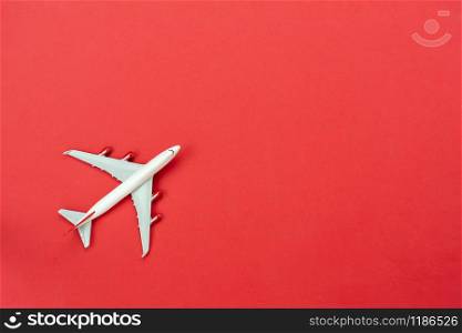 Table top view accessory of accessory travel in holiday background concept.Flat lay of white airplane on modern rustic red paper at home studio office desk.copy space for creative design text.