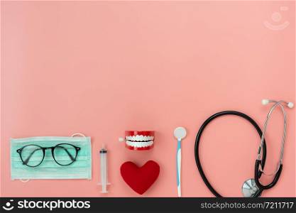 Table top view aerial image of accessories healthcare & medical background.Red heart & denture tools with essential objects on pink paper.Flat lay of idea for dentist doctor treat patient in hospital.