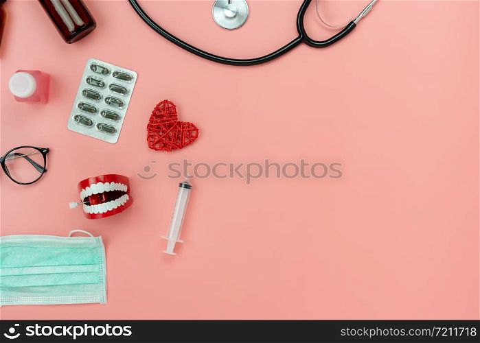 Table top view aerial image of accessories healthcare & medical background.Red heart & denture tools with drugs treatment on pink paper.Flat lay of idea for dentist doctor treat patient in hospital.