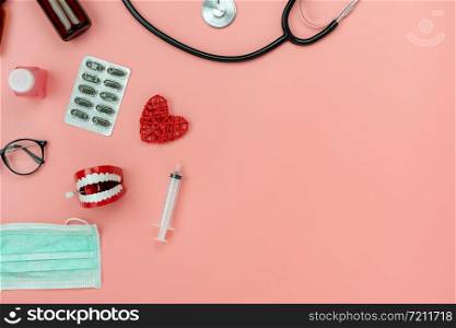 Table top view aerial image of accessories healthcare & medical background.Red heart & denture tools with drugs treatment on pink paper.Flat lay of idea for dentist doctor treat patient in hospital.