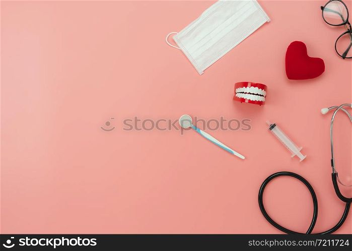 Table top view aerial image of accessories healthcare & medical background.Red heart & denture with essential objects on pink paper.Flat lay of idea for dentist doctor treat patient in hospital.