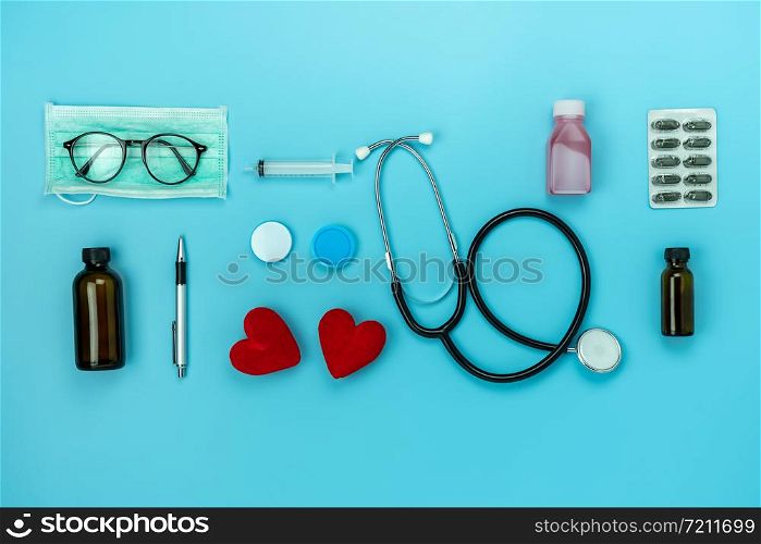 Table top view aerial image of accessories healthcare & medical background concept.Red heart & stethoscope with essential objects on blue paper.Flat lay of idea for doctor treat patient in hospital.