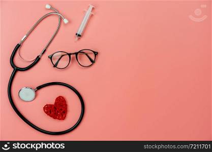 Table top view aerial image of accessories healthcare & medical background concept.Red heart & stethoscope with essential objects on pink paper.Flat lay of idea for doctor treat patient in hospital.