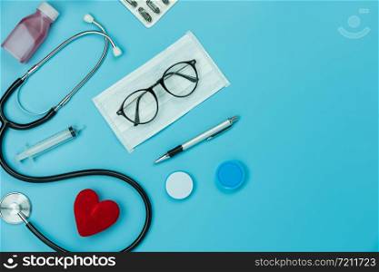 Table top view aerial image of accessories healthcare & medical background concept.Red heart & stethoscope with essential objects on blue paper.Flat lay of idea for doctor treat patient in hospital.