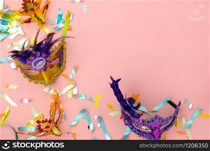 Table top view aerial image of beautiful colorful carnival festival background.Flat lay accessory object the several mask & decor confetti on modern pink paper at home office desk studio.copy space.