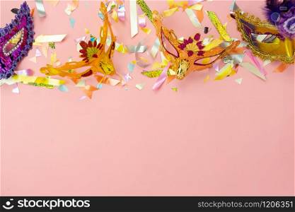 Table top view aerial image of beautiful colorful carnival festival background.Flat lay accessory object the several mask & decor confetti on modern pink paper at home office desk studio.copy space.