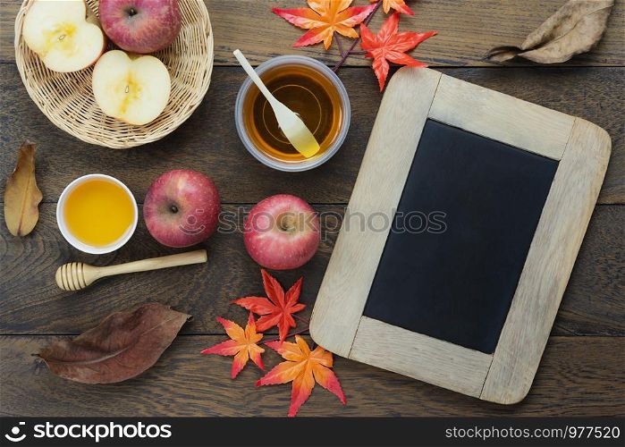 Table top view aerial image of decoration Fall harvest season or Rosh Hashanah day background concept.Flat lay red apple with honey bee and orange maple leaf all objects on modern rustic brown wooden.