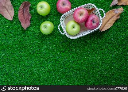 Table top view aerial image of decoration Fall harvest season or Rosh Hashanah day background concept.Flat lay green& red apple in wood basket with dry leaf all objects on rustic grass.Space for text.