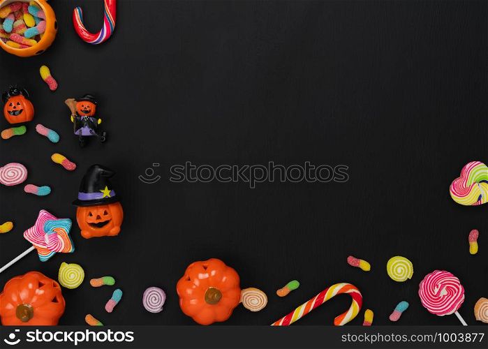 Table top view aerial image of decoration Happy Halloween day background concept.Flat lay accessories essential object to party the pumpkin & sweet candy on black wooden.Space for creative design.
