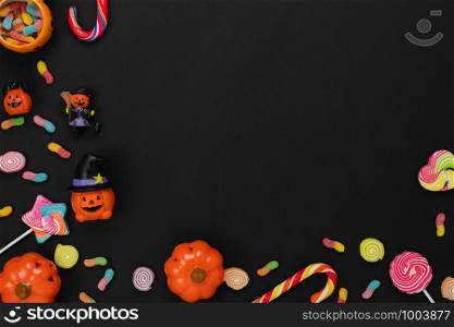 Table top view aerial image of decoration Happy Halloween day background concept.Flat lay accessories essential object to party the pumpkin & sweet candy on black wooden.Space for creative design.