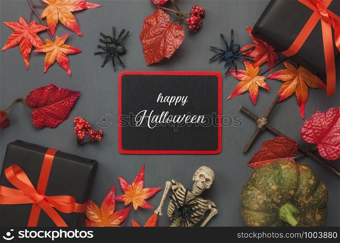 Table top view aerial image of decoration Happy Halloween day background concept.Flat lay accessories essential object to party the pumpkin & flower and gift on black wooden.Text season on blackboard.