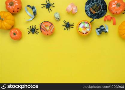 Table top view aerial image of decoration Happy Halloween day background concept.Flat lay accessories essential object to party the pumpkin & sweet candy on yellow paper.Space for design mock up.
