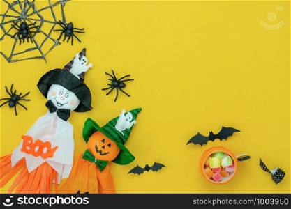 Table top view aerial image of decoration Happy Halloween day background concept.Flat lay accessories essential object to party the cute doll & sweet candy on yellow paper.Space for creative design.
