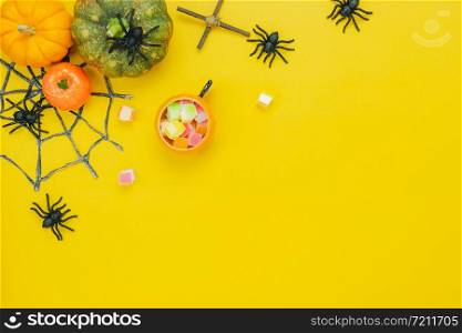 Table top view aerial image of decoration Happy Halloween day background concept.Flat lay accessories essential object to party the pumpkin & sweet candy on yellow paper.Space for creative design.