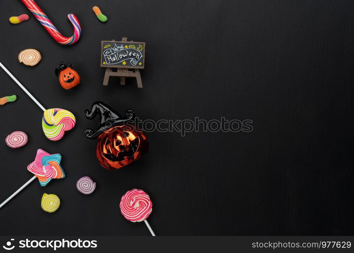 Table top view aerial image of decoration Happy Halloween day background concept.Flat lay accessories essential object to party the pumpkin & sweet candy on black wooden.Space for creative design.