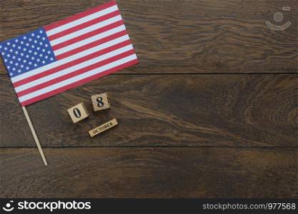 Table top view aerial image of decoration the sign of USA Happy Columbus day on Oct 8,2018 background concept.Flat lay accessories US flag and date & month wood box on modern rustic brown wooden.