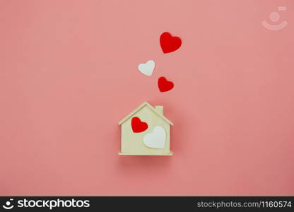 Table top view aerial image of decoration valentine&rsquo;s day background concept.Flat lay essential items colorful pastel love shape with wooden house on modern rustic pink paper.Mock up creative design.