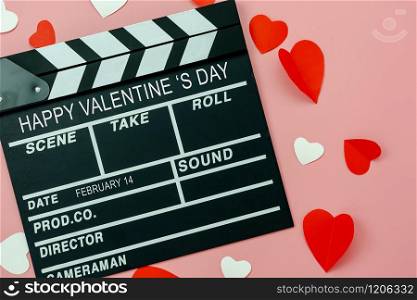 Table top view aerial image of decoration valentine&rsquo;s day background concept.Flat lay essential items colorful love shape paper cut with welcome word on movie clapper with modern pink wallpaper.