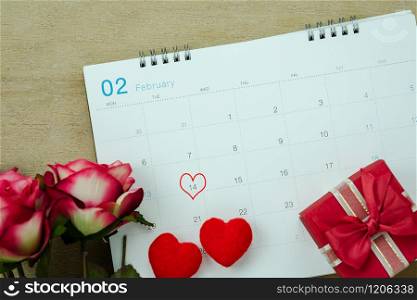 Table top view aerial image of decoration valentine&rsquo;s day background concept.Flat lay arrangement of calendar page of february month with essential items love heart with rose flower on wooden.