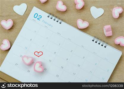 Table top view aerial image of decoration valentine&rsquo;s day background concept.Flat lay arrangement of calendar page of february month with essential items love heart on brown wooden for season.