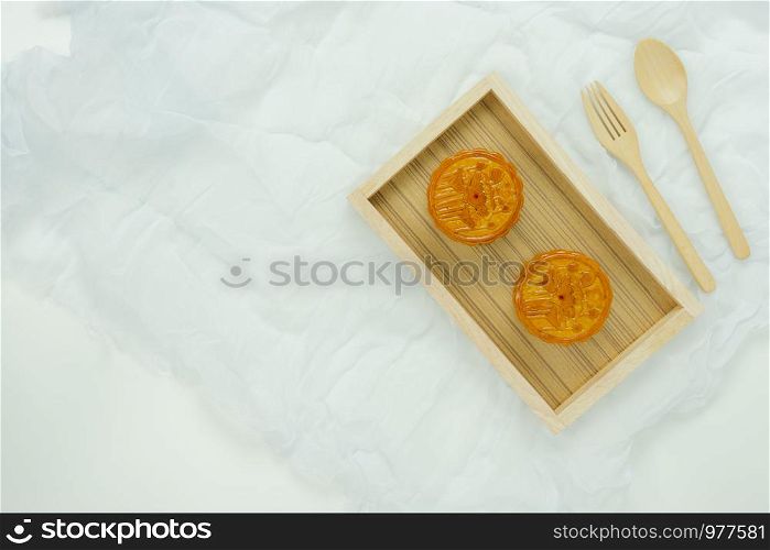 Table top view aerial image of decorations Chinese Moon Festival or lunar new year background concept.Flat lay sweet moon cake & wood spoon and fork with clothing on white wooden.Space for design.