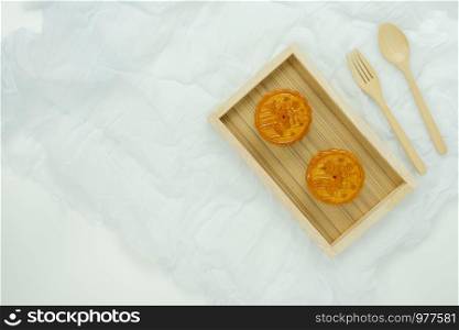 Table top view aerial image of decorations Chinese Moon Festival or lunar new year background concept.Flat lay sweet moon cake & wood spoon and fork with clothing on white wooden.Space for design.