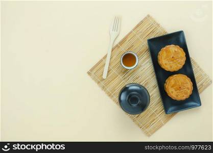 Table top view aerial image of decorations Chinese Moon Festival or lunar new year background concept.Flat lay essential meal set for coffee break of sweet cake & tea with blossom on yellow paper.