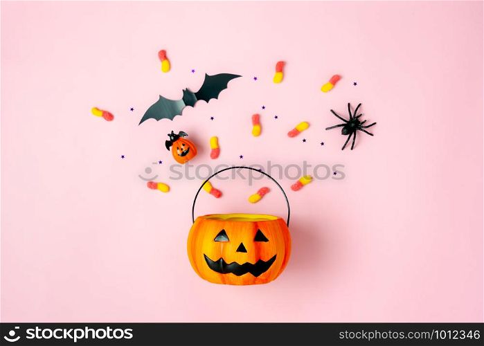 Table top view aerial image of decorations Happy Halloween day background holiday concept.Flat lay objects to party Jack O lantern pumpkins bucket and spider with candy sweet on pink paper.