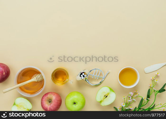 Table top view aerial image of decorations Jewish holiday the Rosh Hashana background concept.Flat lay object sign of variety apple & honey bee cup and wood spoon on modern rustic yellow paper.