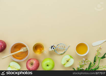 Table top view aerial image of decorations Jewish holiday the Rosh Hashana background concept.Flat lay object sign of variety apple & honey bee cup and wood spoon on modern rustic yellow paper.