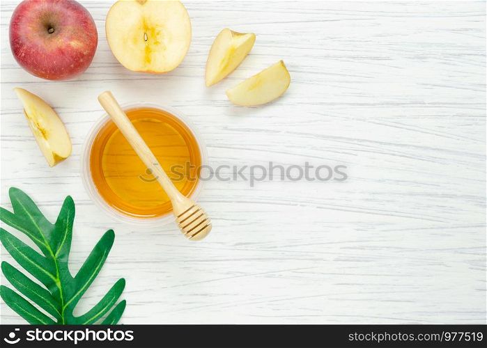 Table top view aerial image of decorations Jewish holiday the Rosh Hashana background concept.Flat lay object fruit of variety apple & honey bee cup and left on modern rustic white wooden plank.