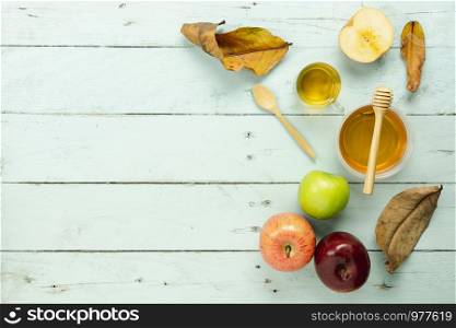 Table top view aerial image of decorations Jewish holiday the Rosh Hashana background concept.Flat lay object sign of variety apple & honey bee cup and wood spoon on modern rustic green wooden wall.