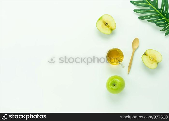 Table top view aerial image of decorations Jewish holiday the Rosh Hashana background concept.Flat lay object sign of variety apple & honey bee cup and wood spoon on modern rustic white wooden wall.