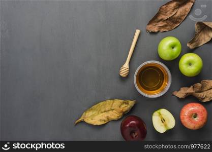 Table top view aerial image of decorations Jewish holiday the Rosh Hashana background concept.Flat lay object sign of variety apple & honey bee cup and wood spoon on modern rustic grey wooden wall.