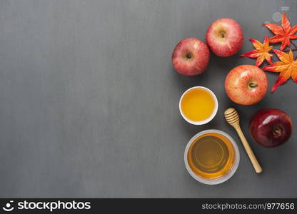 Table top view aerial image of decorations Jewish holiday the Rosh Hashana background concept.Flat lay object sign of variety apple & honey bee cup and wood spoon on modern rustic grey wooden wall.