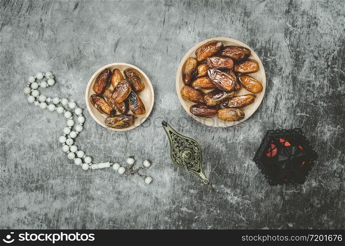 Table top view aerial image of decorations Ramadan Kareem holiday background.Flat lay date with rosary & aladdin lamp & arabic lantern.Halal meal set for fasting is obligatory for Muslim on cement.
