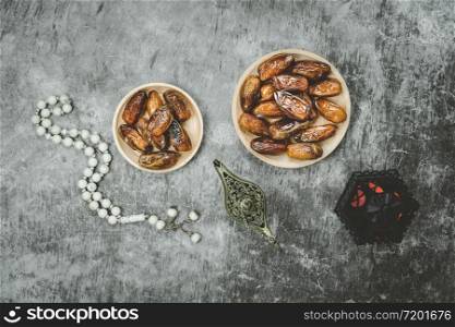 Table top view aerial image of decorations Ramadan Kareem holiday background.Flat lay date with rosary & aladdin lamp & arabic lantern.Halal meal set for fasting is obligatory for Muslim on cement.
