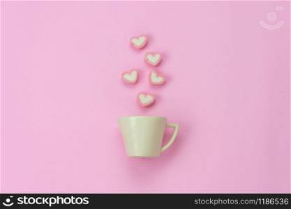 Table top view aerial image of sign valentine&rsquo;s day background concept.Flat lay arrangement white coffee cup with steam heart shape on modern pink paper at home office desk studio.Pastel tone design.