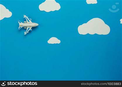 Table top view aerial image of transportation with airplane or travel background concept.Flat lay of aircraft fly on beautiful blue sky with paper cut white cloud with copy space.Design for mock up.