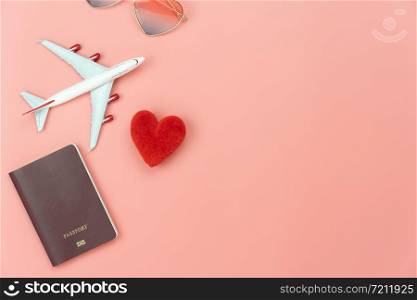 Table top view essential accessory women plan to travel in holiday background.Flat lay of red heart & airplane with passport and love sun glasses on modern pink paper.Love tourism concept.Copy space.