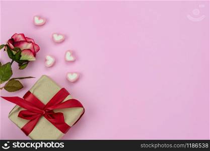 Table top view image of decoration valentine&rsquo;s day background concept.Flat lay red rose and essential symbol love season with gift box on modern rustic pink paper at home office desk studio.