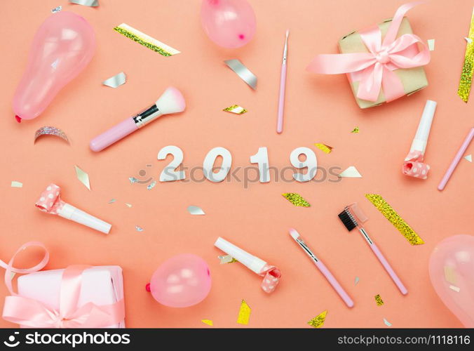 Table top view of Merry Christmas decorations & Happy new year 2019 ornaments concept.Flat lay essential difference objects gift box & text with golden confetti on modern pink paper background.