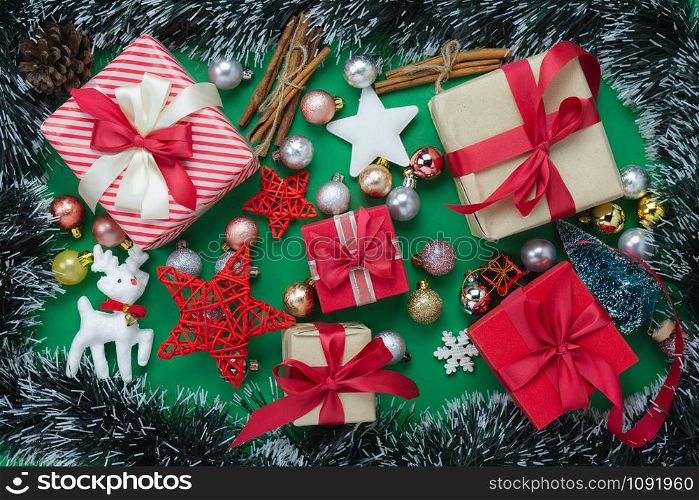 Table top view of Merry Christmas decorations & Happy new year ornaments concept.Flat lay essential difference objects gift box & fir tree on modern green paper background at home studio office desk.