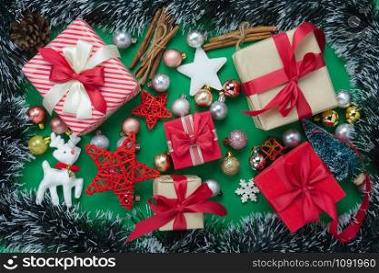 Table top view of Merry Christmas decorations & Happy new year ornaments concept.Flat lay essential difference objects gift box & fir tree on modern green paper background at home studio office desk.